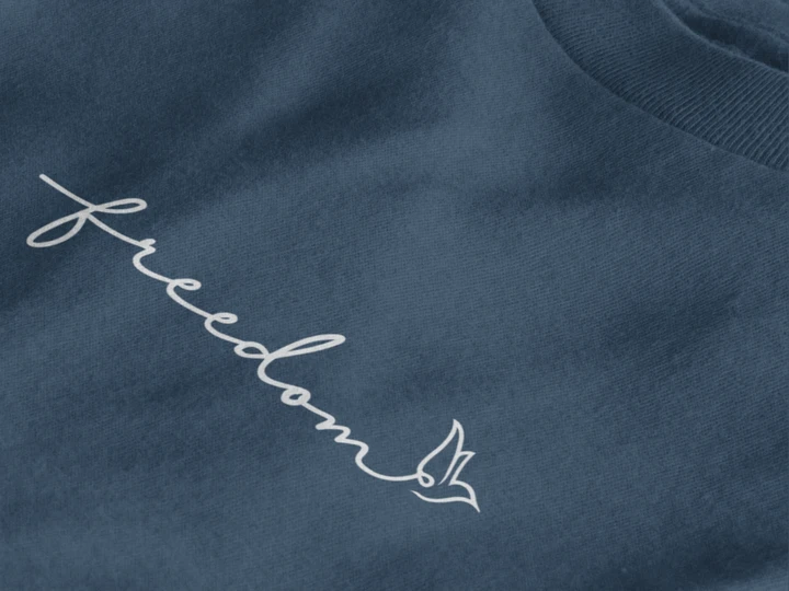 Close-up of a midnight navy crewneck t-shirt featuring the word 'freedom' embroidered in white script across the chest, accompanied by a small white bird silhouette.