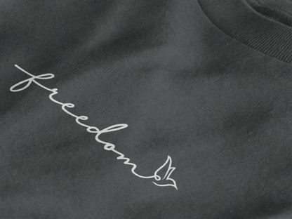 Close-up of a Graphite t-shirt featuring a white script word 'freedom' and a small bird outline on the chest.