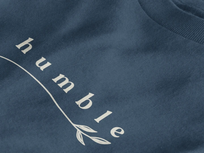 Close-up of a midnight navy crewneck t-shirt featuring a black graphic print that reads 'humble' in a stylized font with a leaf motif.