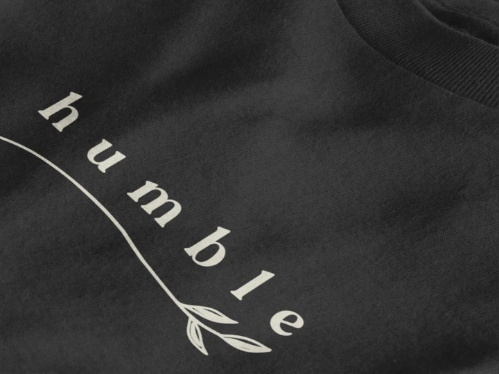 Close-up of a jet black crewneck t-shirt featuring a black graphic print that reads 'humble' in a stylized font with a leaf motif.