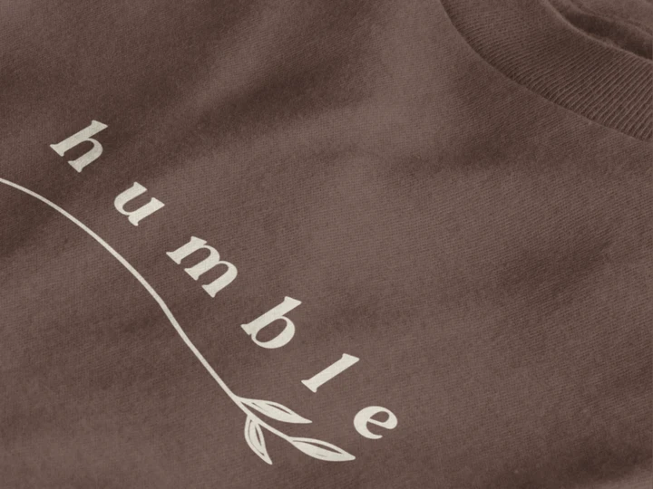 Close-up of a dark mocha crewneck t-shirt featuring a black graphic print that reads 'humble' in a stylized font with a leaf motif.