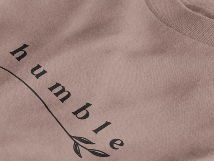 Close-up of a taupe crewneck t-shirt featuring a black graphic print that reads 'humble' in a stylized font with a leaf motif.