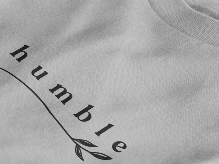 Close-up of a heather grey crewneck t-shirt featuring a black graphic print that reads 'humble' in a stylized font with a leaf motif.