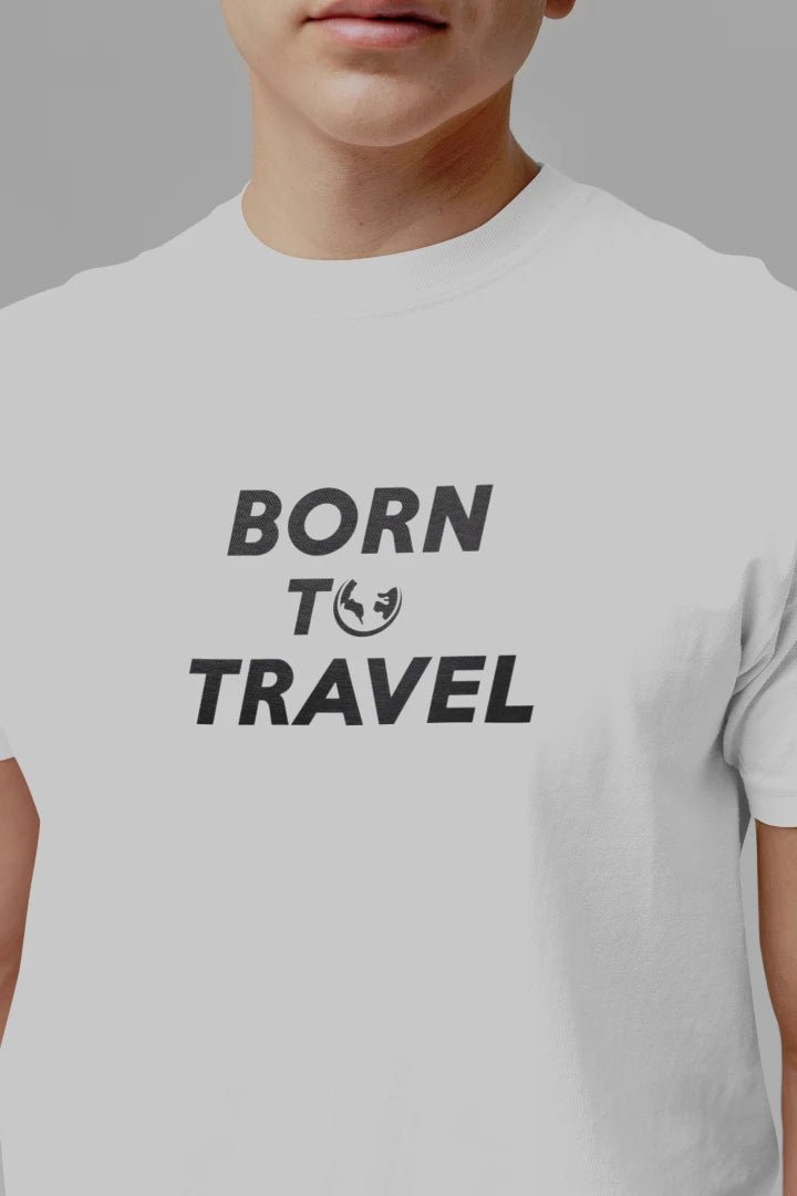 A close-up of a person wearing a Pure White short-sleeve t-shirt with the text 'BORN TO TRAVEL' printed in black on the chest.
