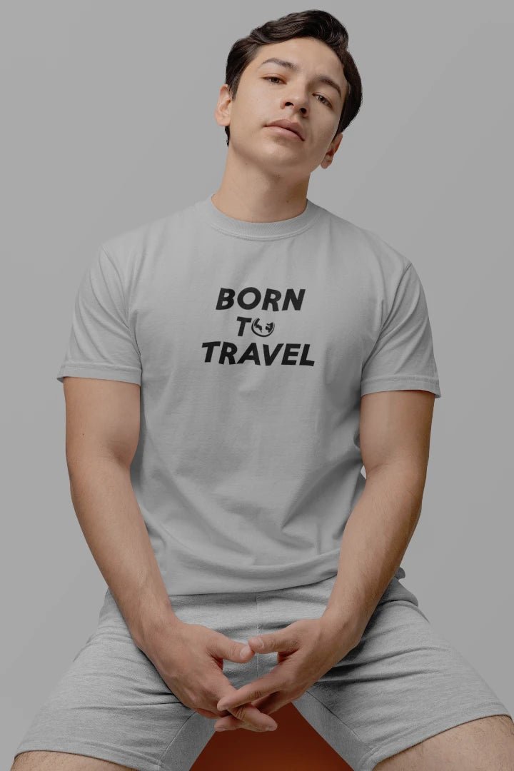 A man wearing a Heather Grey crewneck t-shirt with the black text 'BORN TO TRAVEL' printed on the chest, paired with matching light gray shorts, set against a solid gray background.