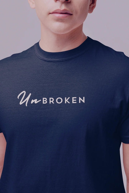 A close-up of a person wearing a navy blue crewneck t-shirt with the text 'Un-BROKEN' printed in white across the chest.